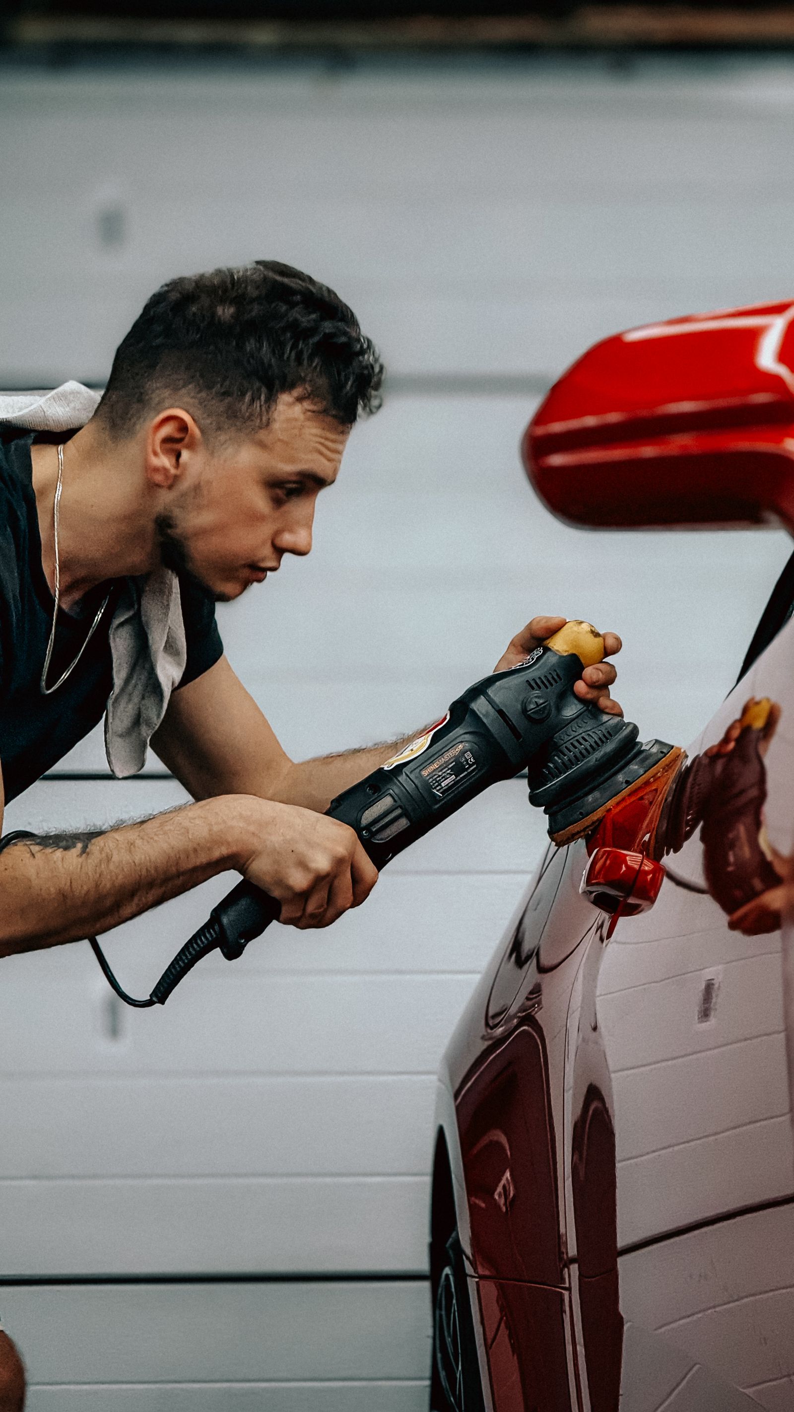 Technician polishing a red car with a buffer