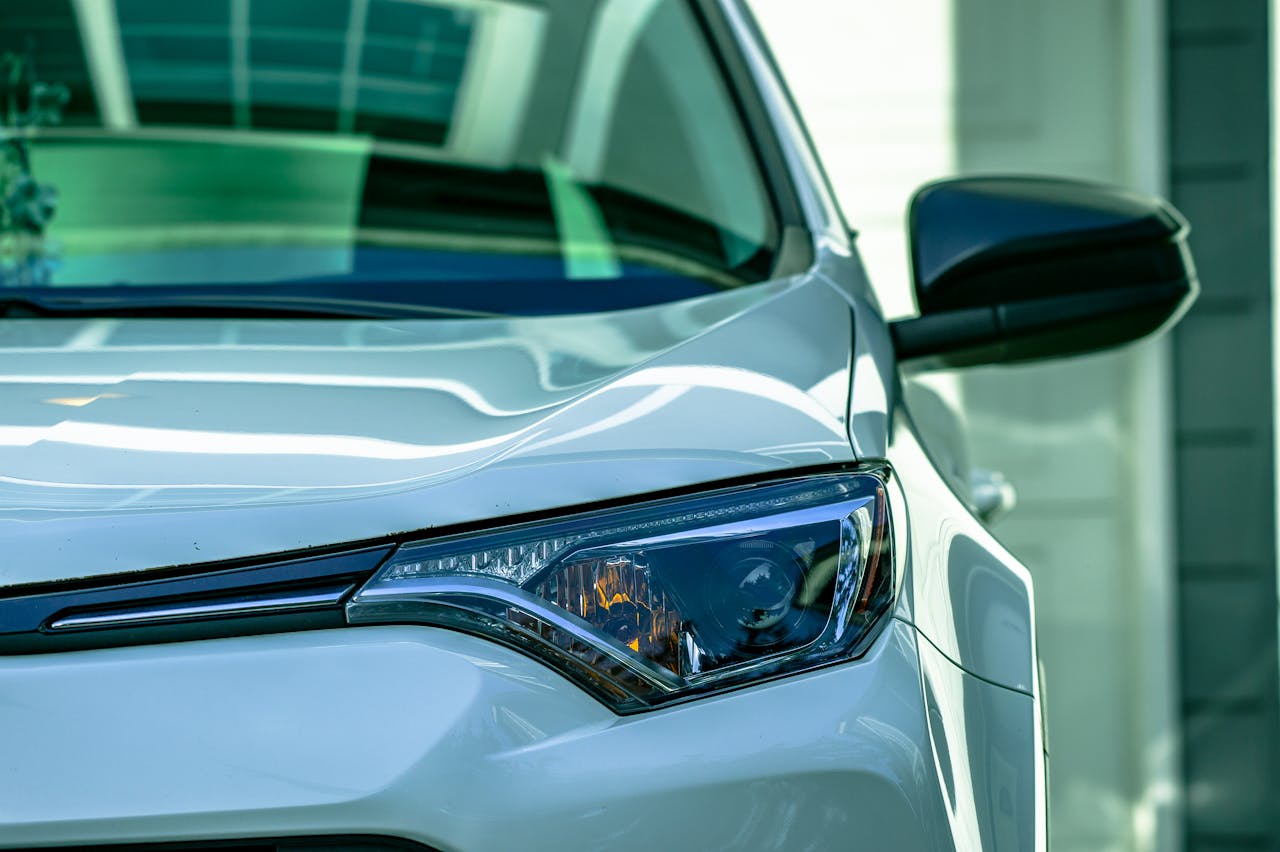 Detailed view of a stylish white car's headlight with reflective sleek design.